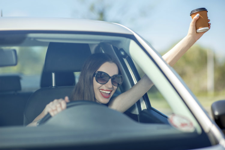 Junge Frau mit Kaffee im Auto