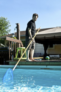 Mann reinigt seinen Pool im Garten